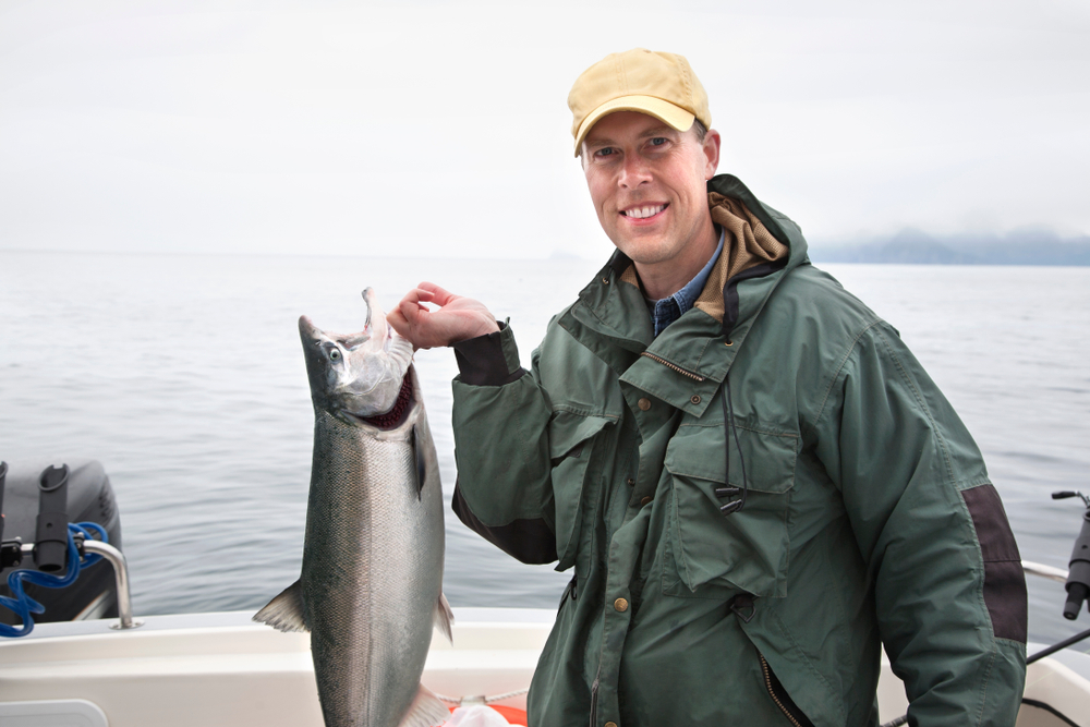 Man holding salmon while on a unique corporate retreat location